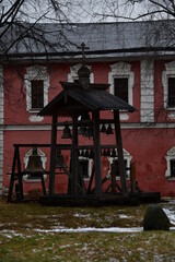 Church bells on a wooden bell tower on the territory of the monastery. Falling snow on the ground. Winter.