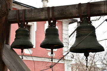 Close-up of the bells. The bells are suspended from a wooden beam. Bells with metallic patterns.