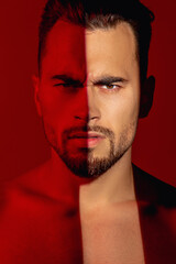 Young, athletic and strong guy. Sexy sporty man, macho. He has a naked torso on a red background. A ray of light falls on one eye. The guy has a very serious look