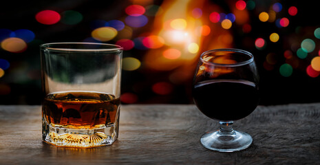 a glass of whiskey and wine on wood bar, romantic dinner setting.	
