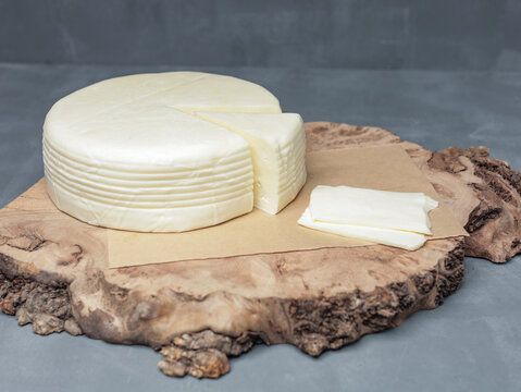 farm cheese on wooden stand on gray background