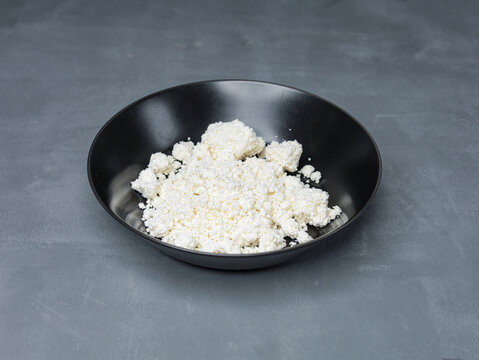natural cottage cheese in a black plate on a gray table