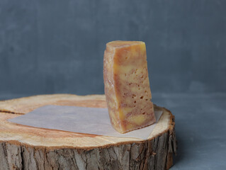 cheese on a wooden stand with paper on a gray background - 478158833