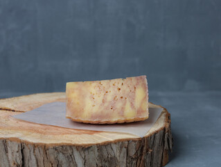 cheese on a wooden stand with paper on a gray background - 478158862