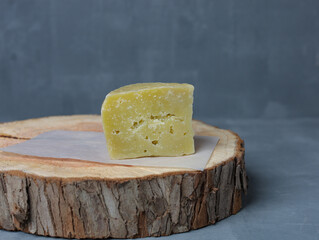 cheese on a wooden stand with paper on a gray background - 478158890