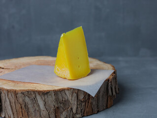 cheese on a wooden stand with paper on a gray background - 478159035