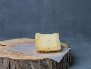 cheese on a wooden stand with paper on a gray background - 478159205