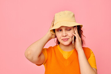 pretty woman communicates on the phone in yellow hat fashion pink background unaltered