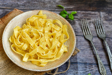 Italian food . Fresh home made  tagliatelle vegetarian  egg pasta  with ,parmesan cheese ,fresh parsley  and black pepper.Pasta cacio e pepe