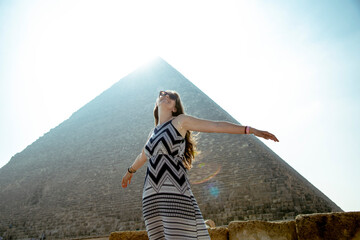 Happy woman in Giza desert landscape with pyramids and blue sky in background in Egypt