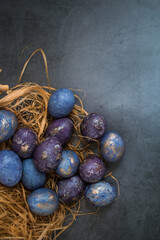 Easter card with a copy of the place for the text. Purple, blue and golden eggs on a dark background. The purple hue trend of 2022 is very relevant. Natural dye karkade tea. Top view.