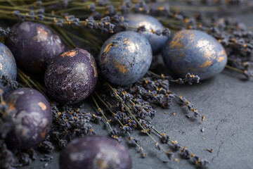 Easter card with a copy of the place for the text. Purple, blue and golden eggs with lavender on a dark background. The purple hue trend of 2022 is very relevant. Natural dye karkade tea. Top view.