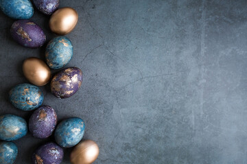 Easter card with a copy of the place for the text. Purple, blue and golden eggs on a dark background. The purple hue trend of 2022 is very relevant. Natural dye karkade tea. Top view.