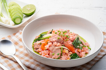 Thai pink fried rice in white plate,stir fry rice with red sauce and pork meat mix with tomato kale and onion