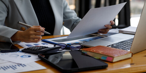 Close up businesswoman hand using calculator and writing make a note with calculate about finance accounting. Report finance accounting concept