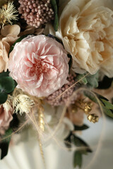 Beautiful preserved flower bouquet in ceramic vase on white table. Stylish bouquet in peach tones closeup.