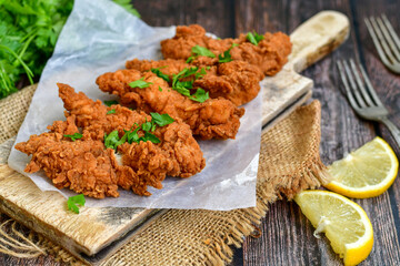 Crispy  deep fried   chicken strips and wedges potato. Breaded  with cornflakes chicken  breast fillets  with chilly peppers and fresh   basil on wooden rustic background