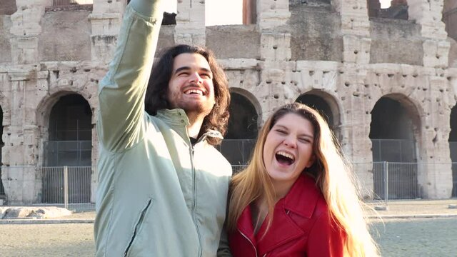 Young couple traveling to Rome. The beautiful couple is taking funny selfies in front of the Colosseum.