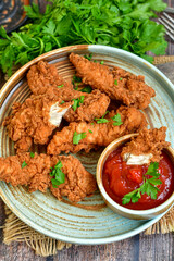
 Crispy  deep fried   Chicken    strips and Wedges potato. Breaded  with cornflakes chicken  breast fillets  with chilly peppers and fresh   basil on wooden rustic background