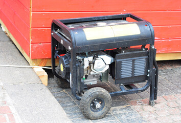 A mobile gasoline generator with two wheels. A close-up of a portable two-fuel, gasoline and...