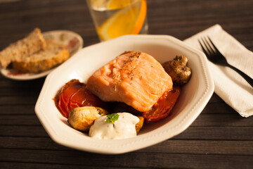 simmered slice of salmon with tomato spinon and coconut sauce in a white bowl