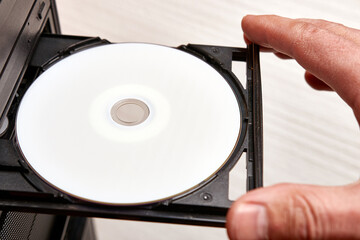 A man inserts a disc into a disc player on his computer. Technologies of information carriers of CD, DVD, BD format.