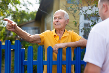Farm neighbors talk at the border of garden plot