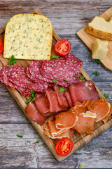 Italian  dried thinly sliced   artisan  pork salami Milano ,  mediterranean parmesan cheese, tomatoes   and fresh basil on wooden background .Rustic  home made italian snack.