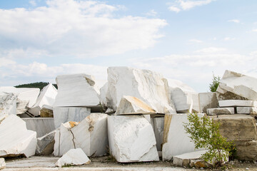 Large white marble stones in an old abandoned quarry. White marble texture. Smooth cuts on the...