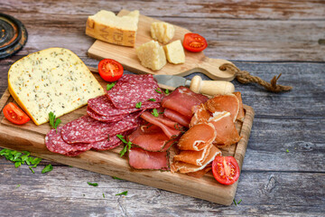 Italian  dried thinly sliced   artisan  pork salami Milano ,  mediterranean parmesan cheese, tomatoes   and fresh basil on wooden background .Rustic  home made italian snack.