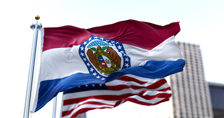 the flag of the US state of Missouri waving in the wind with the American flag blurred in the background