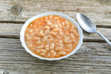   Homemade bean soup .Steamed white beans in tomato sauce  on a wooden background  