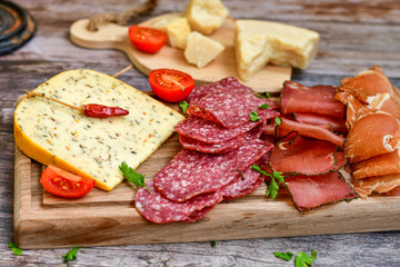 Italian  dried thinly sliced   artisan  pork Salami Milano ,  mediterranean Parmesan cheese, tomatoes   and fresh basil on wooden background .Rustic  home made Italian snack.