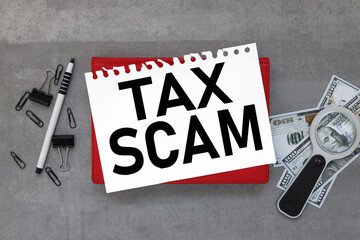 Tax Scam. On the desktop is a red notepad, reports, a white sheet of paper. Business concept