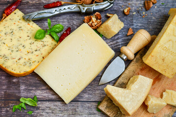  Set of different kinds ot delicious   Italian hard  cheeses,  cheese knives  and walnuts on wooden cheese board.Parmesan. Top view.