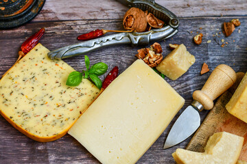  Set of different kinds ot delicious   Italian hard  cheeses,  cheese knives  and walnuts on wooden cheese board.Parmesan. Top view.