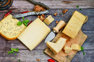  Set of different kinds ot delicious   Italian hard  cheeses,  cheese knives  and walnuts on wooden cheese board.Parmesan. Top view.