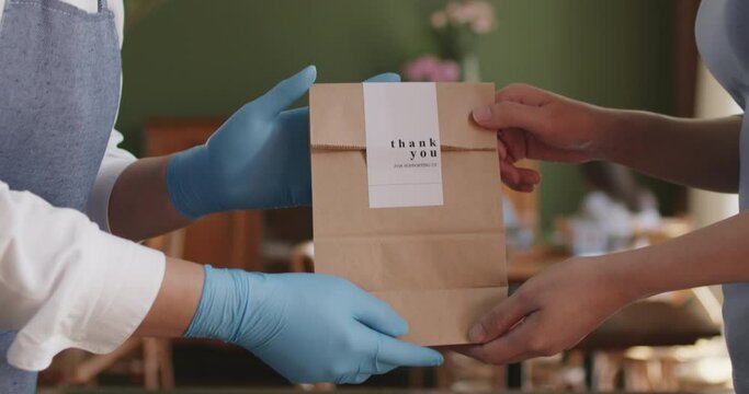 Asia people woman hand glove or face mask happy enjoy buy fast food carry send paper box pick up take home to-go lunch meal. Small cafe coffee shop work with wrap care new normal for SME omni channel.