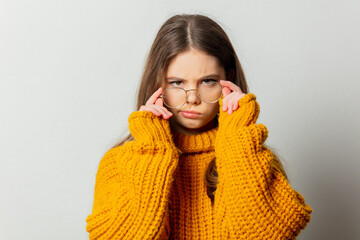 Beautiful girl in glasses and yellow sweater on white background