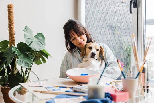 Woman with dog near table with painting supplies