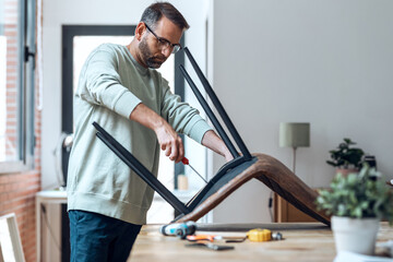 Handsome carpenter man arranging home furniture in the living room.