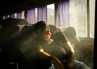 Fototapeta na wymiar Man wearing a toxic gas mask sleeping in a bus amidst green smoke. Reference to the manufacture and use of drugs, mention of the Braking Bad series and fire hazards during tourist trips.
