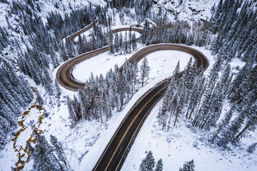 mountain road snakes through pine trees in winter, Colorado