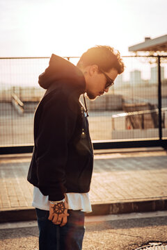 Urban portrait of a stylish tattooed guy during sunset