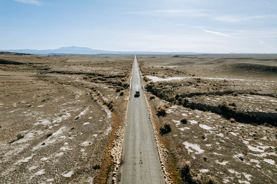 aerial image lonely truck driving on long straight road through desert