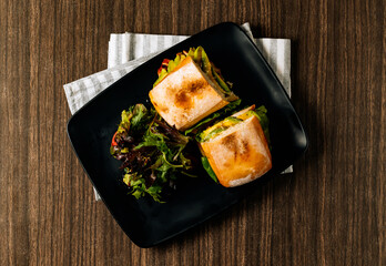 Handmade Chicken Avocado And Mango Chutney Sandwich in black tray top view on dark wood table