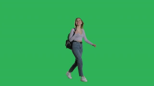 Happy young female model walking with backpack on a Green Screen, Chroma Key. 4k UHD perspective view isolated video.