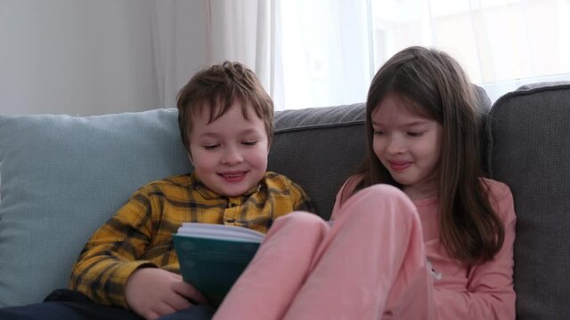little children, brother and sister, friends read a book, play, laugh