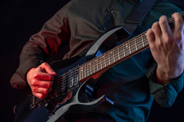Male hands playing electric guitar. Musician man with black guitar at a rock concert