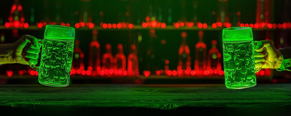 Male hands with mugs of green beer, ale on bar counter. Holiday of Ireland on St. Patrick's Day in irish pub, bar. Festive banner with copy space. National tradition of carnival celebrating